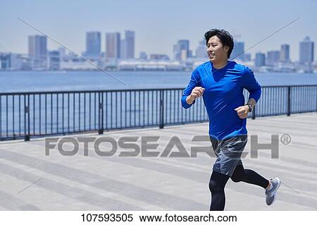 Stock Photography - Young Japanese man running downtown Tokyo. Fotosearch