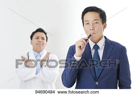 Picture - Young Japanese man smoking electronic cigarette. Fotosearch