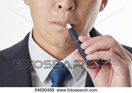 Stock Photograph - Young Japanese man smoking electronic cigarette. Fotosearch