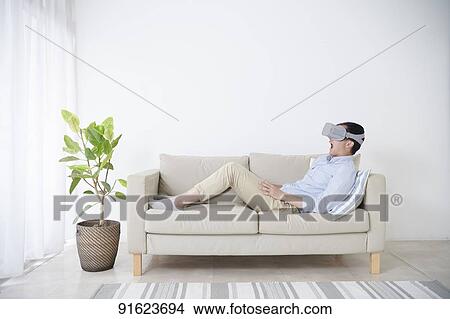 Picture - Young Japanese man using VR goggles. Fotosearch