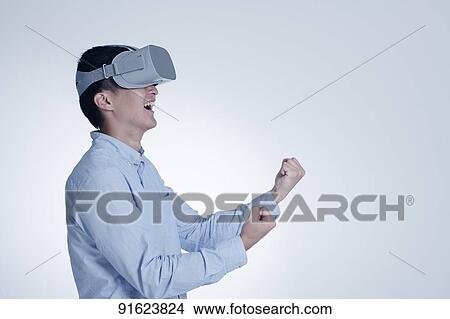 Picture - Young Japanese man using VR goggles. Fotosearch