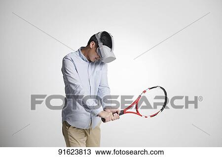 Stock Image - Young Japanese man using VR goggles. Fotosearch