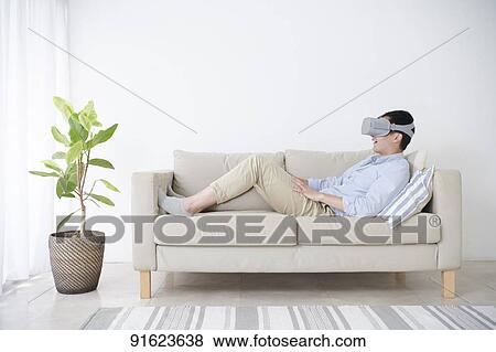 Stock Photo - Young Japanese man using VR goggles. Fotosearch