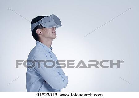 Stock Photo - Young Japanese man using VR goggles. Fotosearch