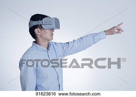 Stock Photograph - Young Japanese man using VR goggles. Fotosearch