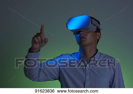 Stock Photograph - Young Japanese man using VR goggles. Fotosearch
