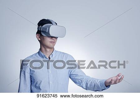 Stock Photography - Young Japanese man using VR goggles. Fotosearch