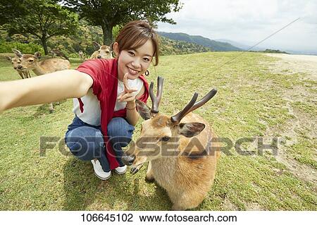 Stock Image - Young Japanese with deer at Nara Park. Fotosearch
