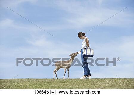 Stock Image - Young Japanese with deer at Nara Park. Fotosearch