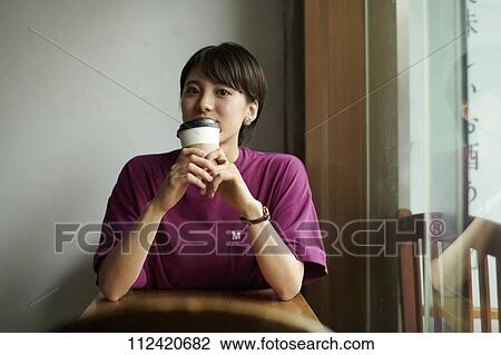 Stock Image - Young Japanese woman at a cafe. Fotosearch