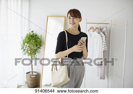 Picture - Young Japanese woman at home getting ready in the morning. Fotosearch