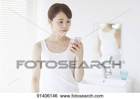Stock Photograph - Young Japanese woman at home getting ready in the morning. Fotosearch