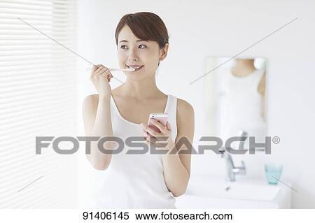 Stock Photography - Young Japanese woman at home getting ready in the morning. Fotosearch