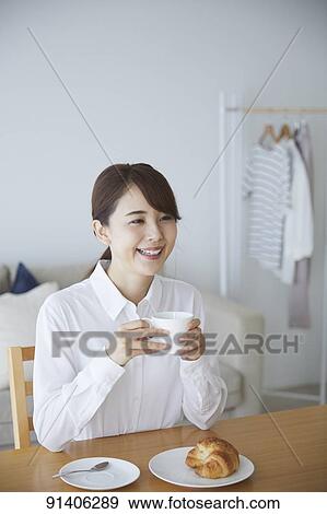 Stock Photo - Young Japanese woman having breakfast at home. Fotosearch