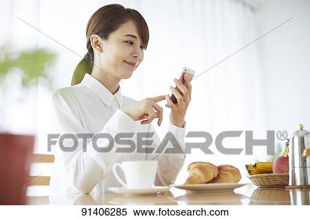 Stock Photography - Young Japanese woman having breakfast at home. Fotosearch