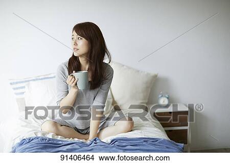 Picture - Young Japanese woman in bed in the morning. Fotosearch