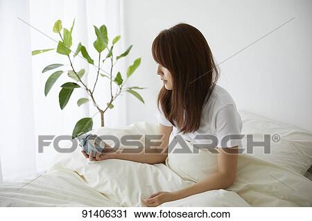 Stock Image - Young Japanese woman in bed in the morning. Fotosearch