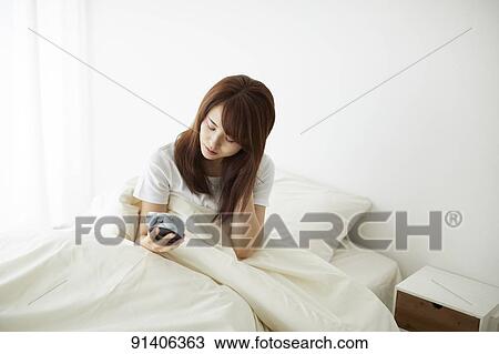 Stock Image - Young Japanese woman in bed in the morning. Fotosearch