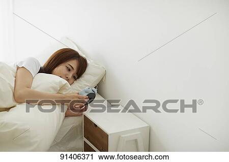 Stock Image - Young Japanese woman in bed in the morning. Fotosearch