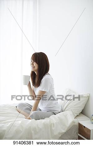 Stock Image - Young Japanese woman in bed in the morning. Fotosearch