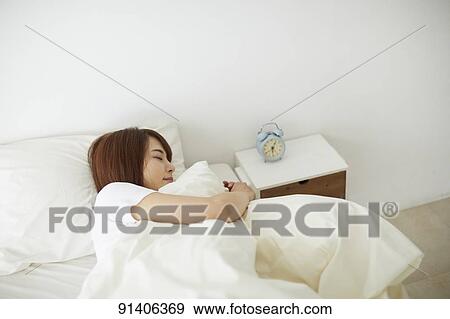 Stock Photo - Young Japanese woman in bed in the morning. Fotosearch