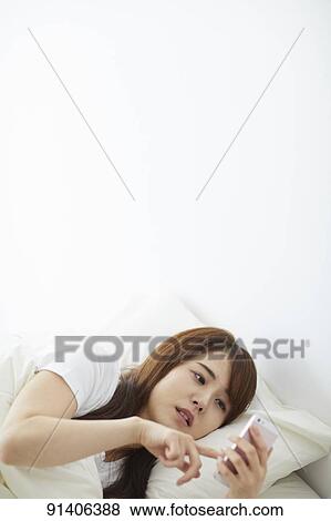 Stock Photo - Young Japanese woman in bed in the morning. Fotosearch