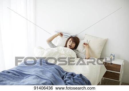 Stock Photograph - Young Japanese woman in bed in the morning. Fotosearch