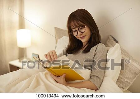 Picture - Young Japanese woman in bed. Fotosearch