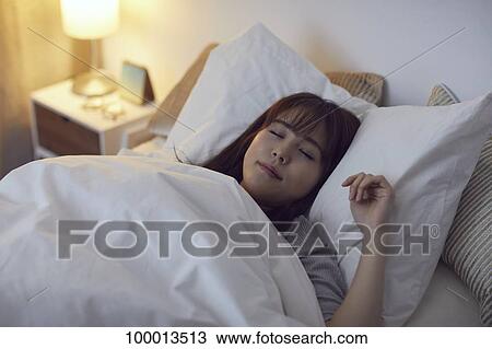 Stock Image - Young Japanese woman in bed. Fotosearch
