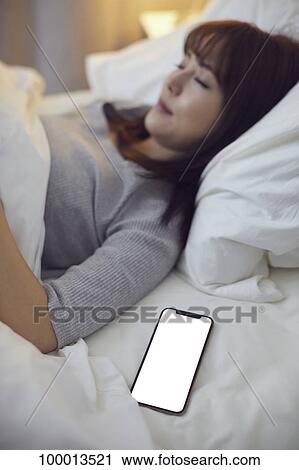 Stock Image - Young Japanese woman in bed. Fotosearch