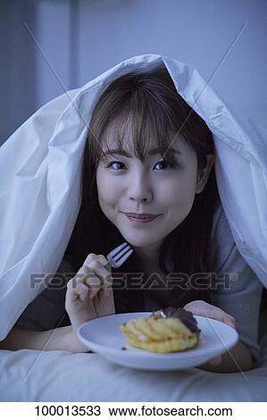Stock Image - Young Japanese woman in bed. Fotosearch