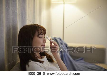 Stock Image - Young Japanese woman in the living room. Fotosearch