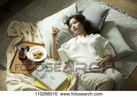 Stock Image - Young Japanese woman in the living room. Fotosearch