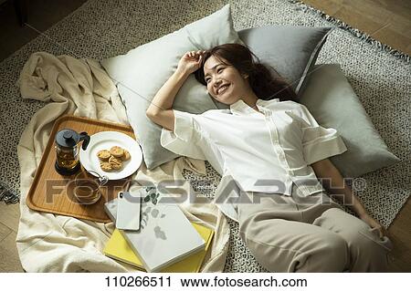 Stock Image - Young Japanese woman in the living room. Fotosearch