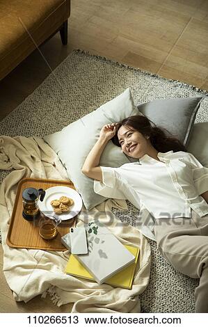 Stock Image - Young Japanese woman in the living room. Fotosearch