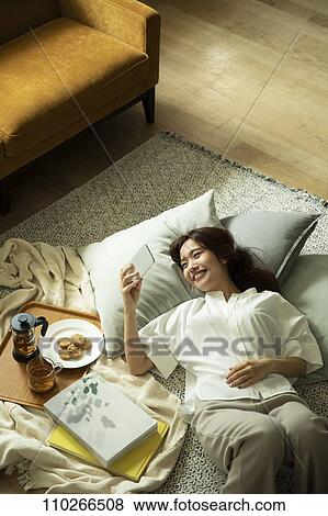 Stock Photo - Young Japanese woman in the living room. Fotosearch