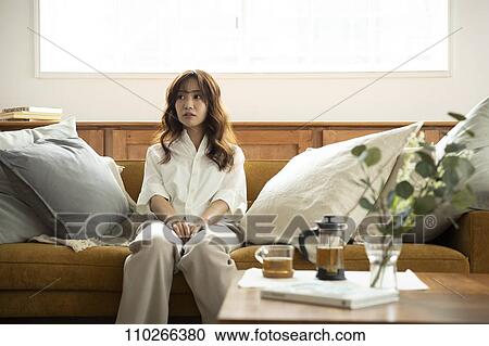 Stock Image - Young Japanese woman on the sofa. Fotosearch