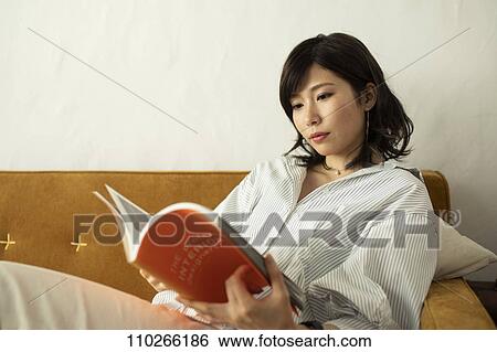 Stock Photograph - Young Japanese woman on the sofa. Fotosearch
