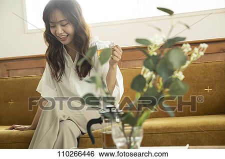Stock Photograph - Young Japanese woman on the sofa. Fotosearch