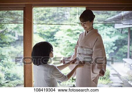 Young Japanese woman putting on traditional kimono View Large Photo Image Picture - Young Japanese woman putting on traditional kimono. Fotosearch