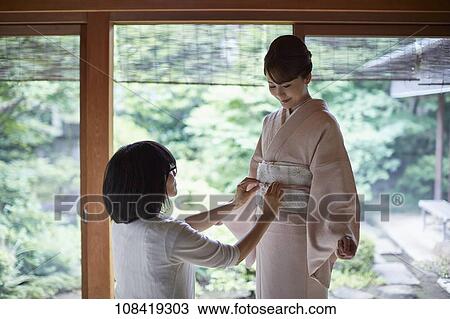 Young Japanese woman putting on traditional kimono View Large Photo Image Stock Image - Young Japanese woman putting on traditional kimono. Fotosearch