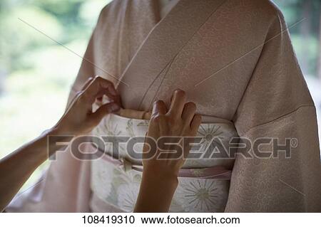 Young Japanese woman putting on traditional kimono View Large Photo Image Stock Image - Young Japanese woman putting on traditional kimono. Fotosearch