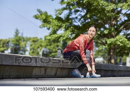 Stock Image - Young Japanese woman running downtown Tokyo. Fotosearch
