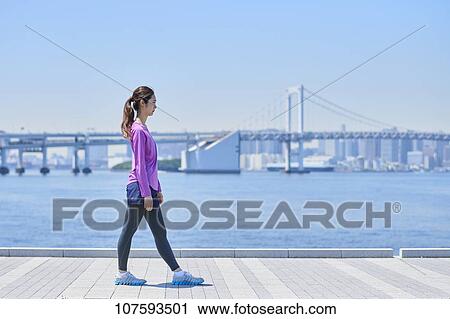 Stock Image - Young Japanese woman running downtown Tokyo. Fotosearch