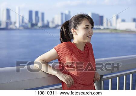 Stock Image - Young Japanese woman running downtown Tokyo. Fotosearch