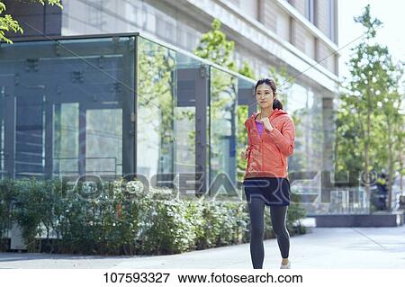 Stock Photo - Young Japanese woman running downtown Tokyo. Fotosearch