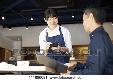 Stock Image - Young Japanese woman working at a restaurant. Fotosearch