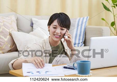 Picture - Young Japanese woman working at home. Fotosearch
