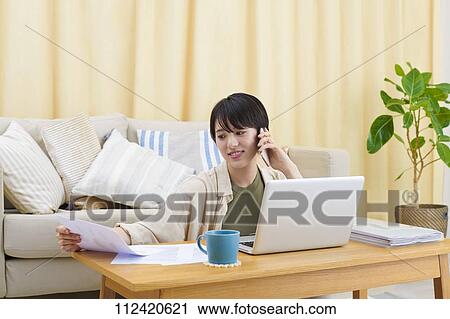 Stock Image - Young Japanese woman working at home. Fotosearch