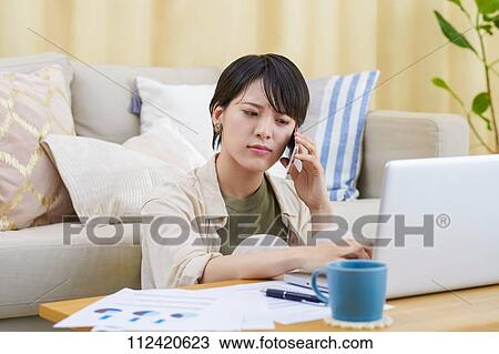 Stock Image - Young Japanese woman working at home. Fotosearch